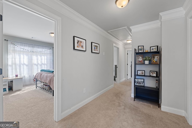 corridor featuring ornamental molding, attic access, light colored carpet, and baseboards