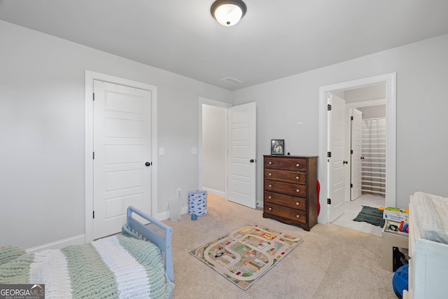 bedroom with ensuite bath, baseboards, visible vents, and light colored carpet