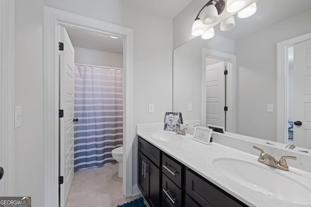 bathroom with double vanity, a sink, toilet, and tile patterned floors