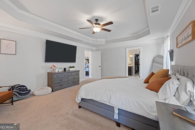 bedroom featuring light carpet, visible vents, a spacious closet, a raised ceiling, and crown molding