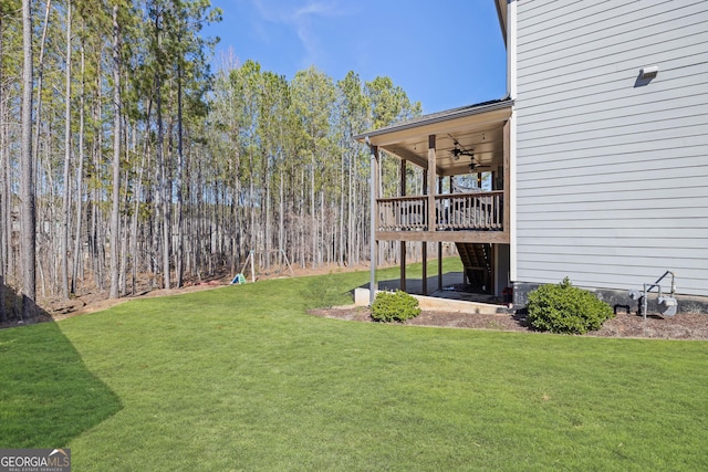 view of yard with ceiling fan and a deck