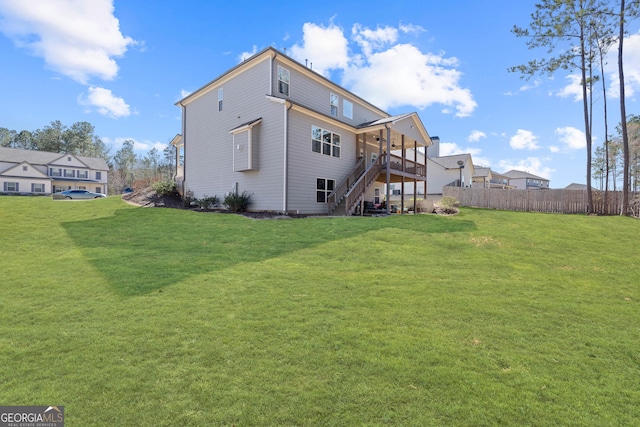 rear view of property featuring a deck, fence, stairway, and a lawn