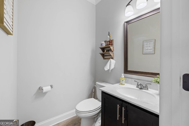 half bathroom with wood finished floors, vanity, toilet, and baseboards