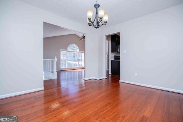 unfurnished dining area with vaulted ceiling, a textured ceiling, wood finished floors, baseboards, and ceiling fan with notable chandelier