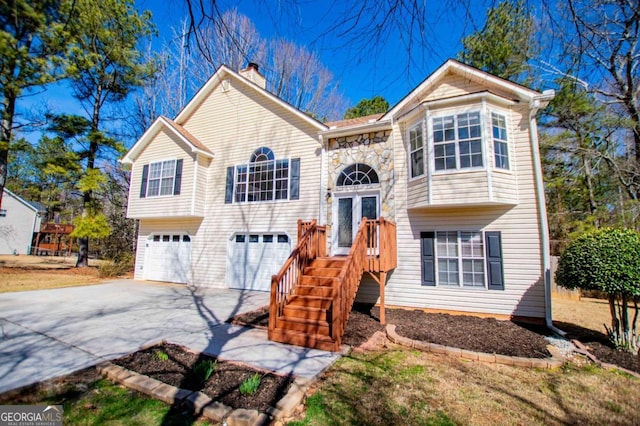 bi-level home with concrete driveway, a chimney, and an attached garage