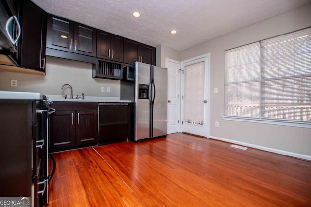 kitchen featuring light countertops, appliances with stainless steel finishes, a sink, wood finished floors, and baseboards