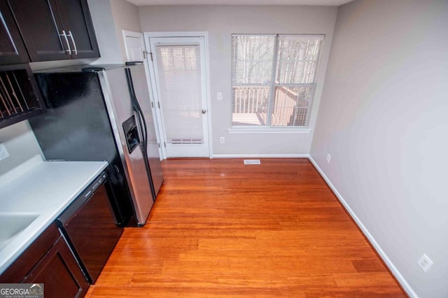 kitchen with black dishwasher, visible vents, baseboards, light countertops, and light wood-style floors