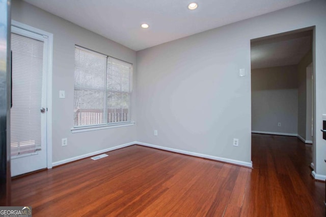 spare room with dark wood-style floors, baseboards, visible vents, and recessed lighting