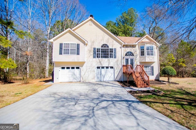 raised ranch with a garage, concrete driveway, a front lawn, and stairs