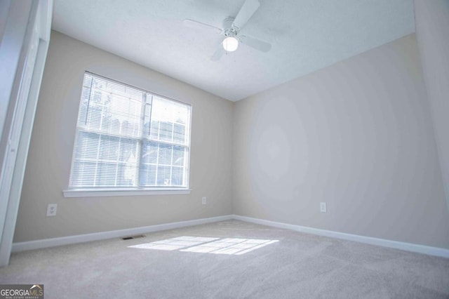 empty room with ceiling fan, baseboards, and light colored carpet