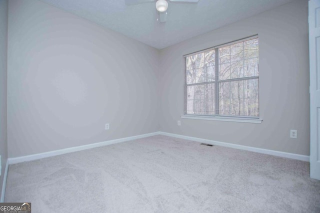 unfurnished room featuring ceiling fan, a textured ceiling, light colored carpet, visible vents, and baseboards