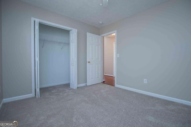 unfurnished bedroom with carpet, a closet, ceiling fan, a textured ceiling, and baseboards