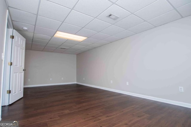 unfurnished room featuring dark wood-type flooring, a paneled ceiling, and baseboards