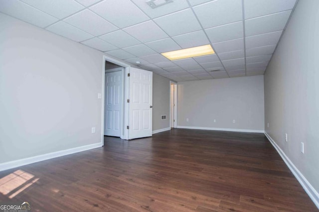 unfurnished room featuring dark wood-type flooring, a drop ceiling, visible vents, and baseboards