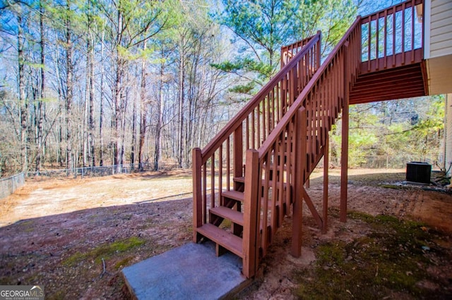 view of yard with central AC, fence, and stairs