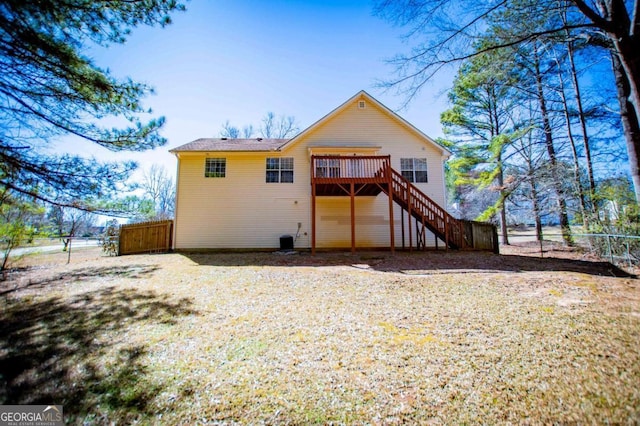 rear view of house with a deck, fence, and stairway