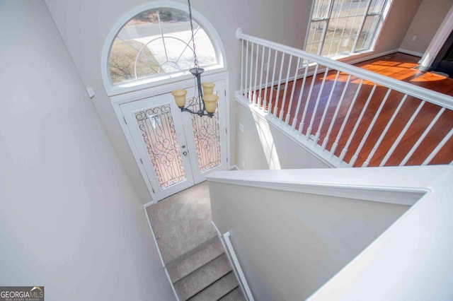 staircase featuring a chandelier and french doors