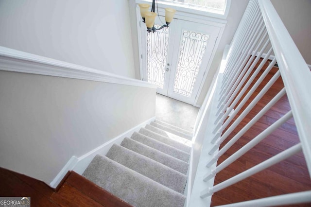 stairs with baseboards, a chandelier, and wood finished floors