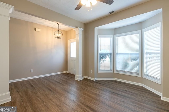 interior space featuring dark wood-style floors, a healthy amount of sunlight, and ornate columns