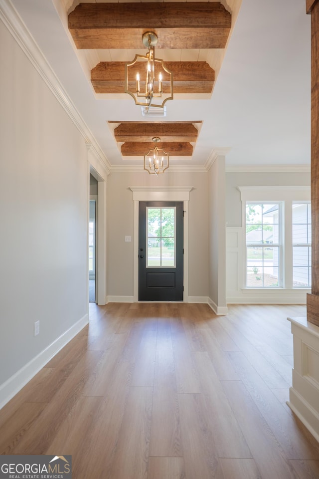 foyer with ornamental molding, wood finished floors, and an inviting chandelier