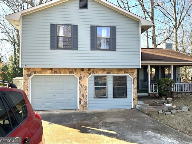 split level home with an attached garage, covered porch, stone siding, concrete driveway, and a chimney