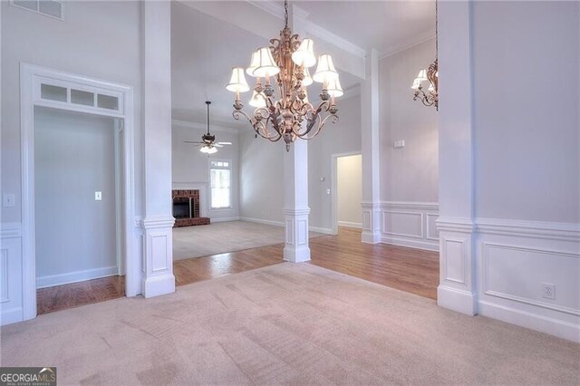 unfurnished dining area with a fireplace, visible vents, a decorative wall, ornamental molding, and light carpet