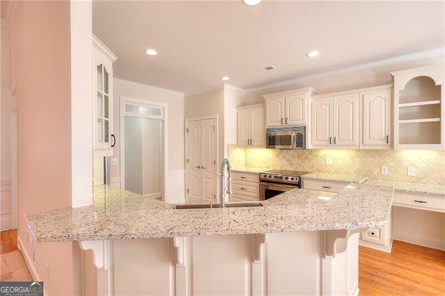 kitchen with stainless steel appliances, light stone counters, a peninsula, and a kitchen bar