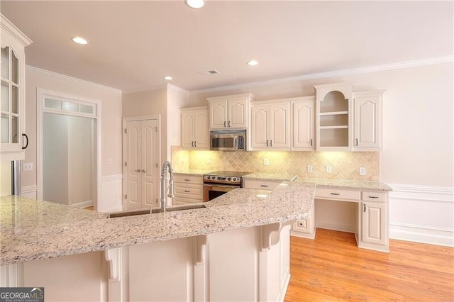 kitchen featuring glass insert cabinets, a breakfast bar, light stone counters, stainless steel appliances, and a sink