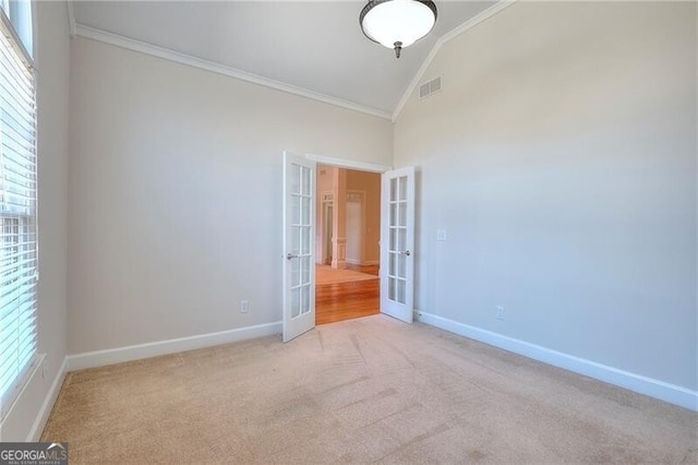 empty room with light carpet, visible vents, baseboards, ornamental molding, and french doors