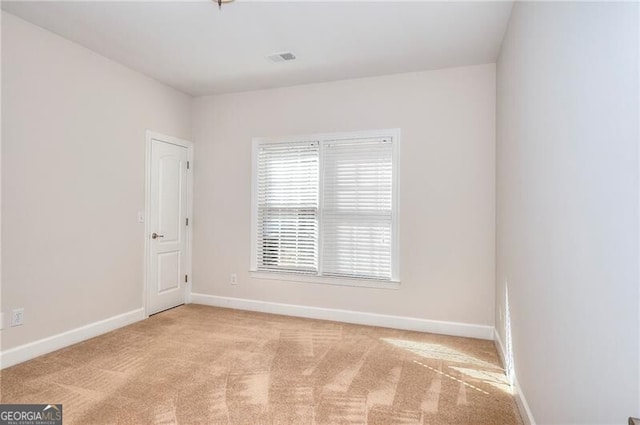 spare room featuring visible vents, baseboards, and light colored carpet