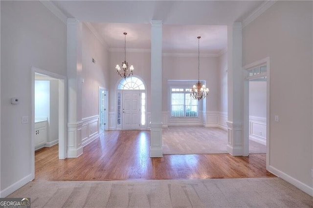 foyer with ornate columns, crown molding, and an inviting chandelier