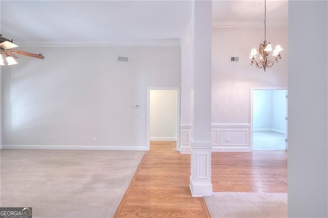 unfurnished room with ornamental molding, visible vents, light wood-style floors, and ceiling fan with notable chandelier