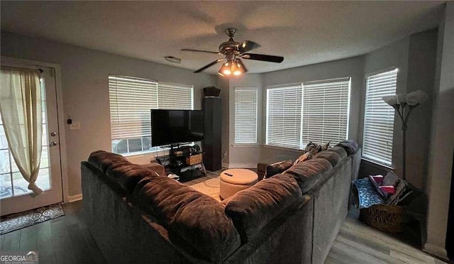 living room with a ceiling fan, baseboards, visible vents, and light wood finished floors