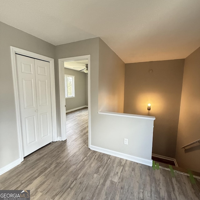 spare room with a textured ceiling, baseboards, and wood finished floors