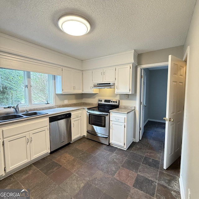 kitchen with under cabinet range hood, a sink, white cabinetry, light countertops, and appliances with stainless steel finishes