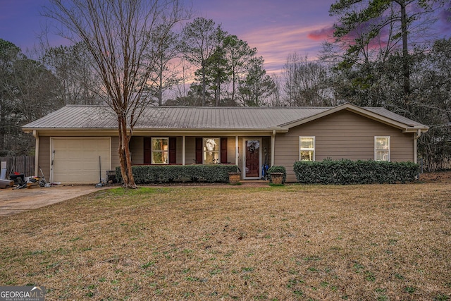 single story home with a garage, metal roof, a lawn, and driveway