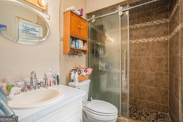 bathroom with a stall shower, vanity, and toilet