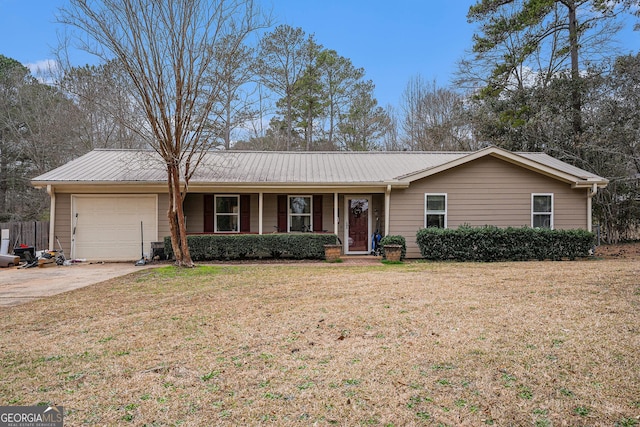 ranch-style house featuring an attached garage, metal roof, concrete driveway, and a front yard