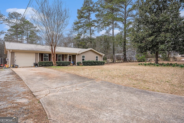 ranch-style house featuring a garage, metal roof, and driveway