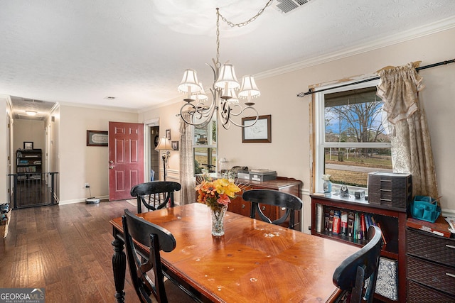 dining area with a textured ceiling, a notable chandelier, wood finished floors, visible vents, and crown molding