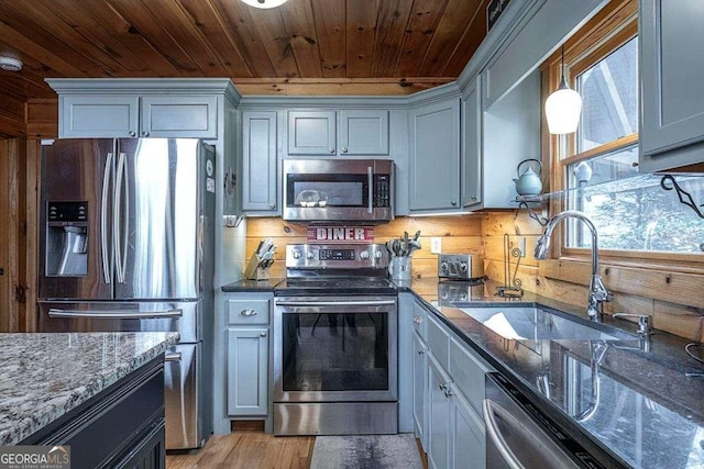 kitchen with stainless steel appliances, decorative backsplash, wood ceiling, a sink, and dark stone countertops