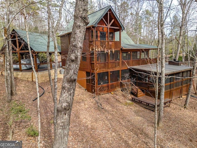 back of house with log veneer siding and a sunroom