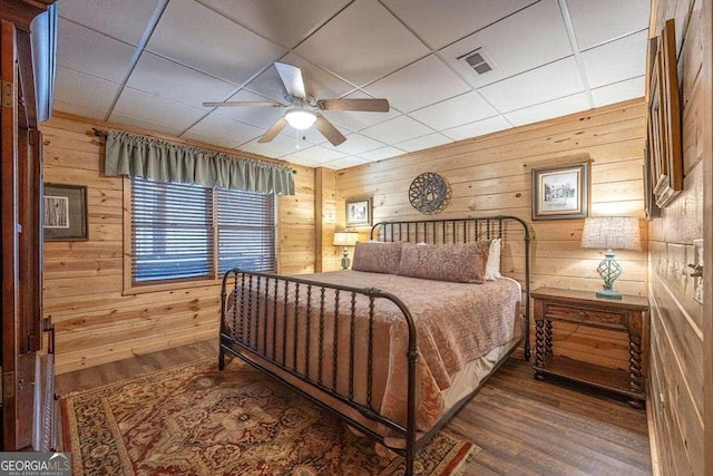 bedroom featuring wood walls, visible vents, and wood finished floors