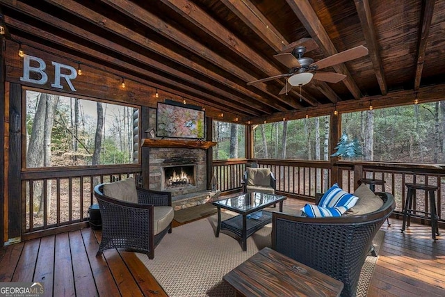 sunroom with lofted ceiling, an outdoor stone fireplace, and a ceiling fan