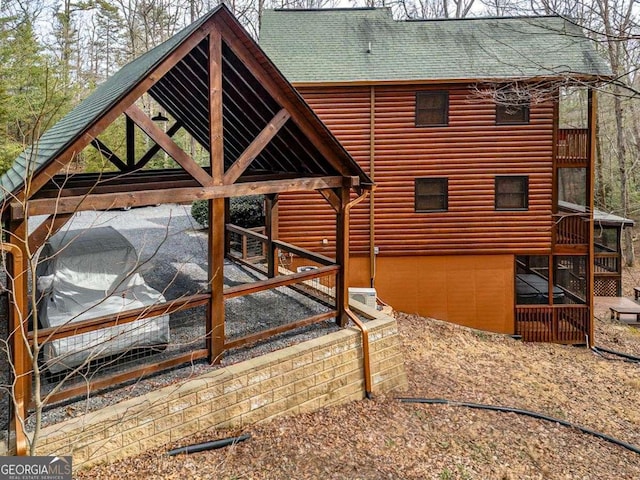 exterior space with a shingled roof and log veneer siding