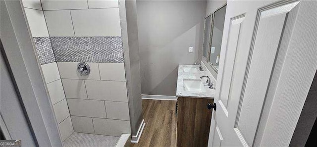 bathroom with double vanity, wood finished floors, a sink, and a shower stall