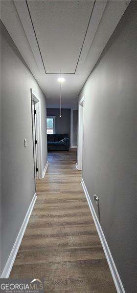 hallway with attic access, baseboards, and wood finished floors