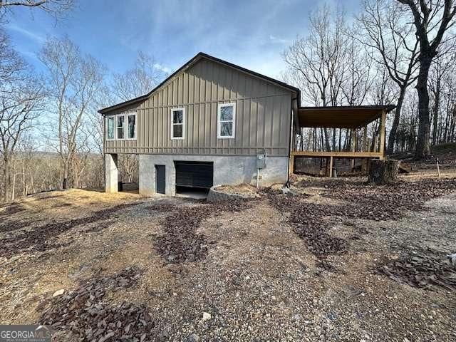 view of property exterior featuring dirt driveway, an attached carport, and board and batten siding