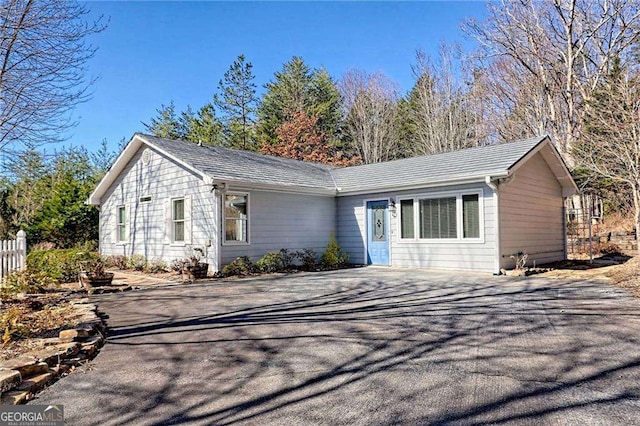 ranch-style home with driveway and fence