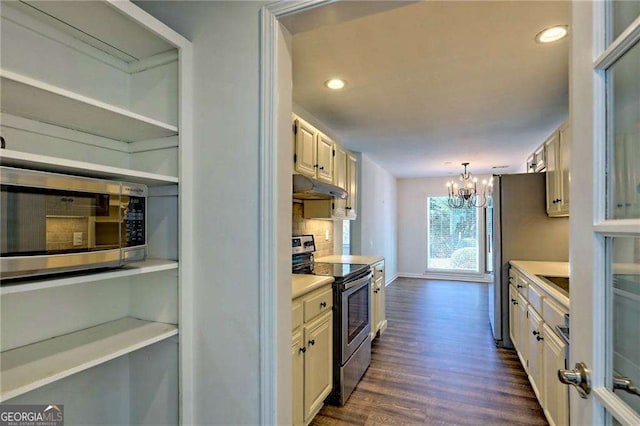 kitchen featuring dark wood-style floors, stainless steel appliances, light countertops, hanging light fixtures, and under cabinet range hood